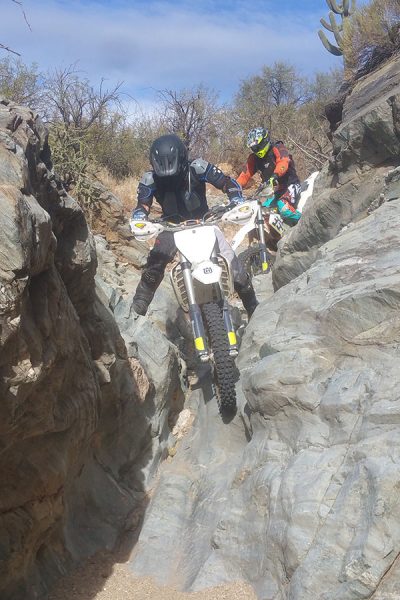 Two riders navigating a narrow rock canyon