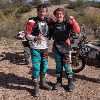 A father and son in full riding gear giving thumbs up